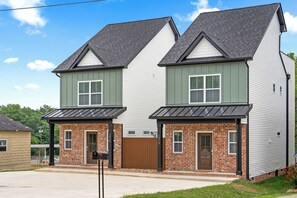 A two-story residential building with a brick facade and white siding. - Adam's Downtown Retreat with 2 Rooftop Patios (Clarksville)