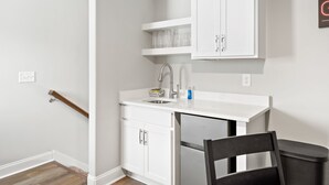 Una cocina compacta con muebles blancos, lavavajillas integrado y una pequeña encimera.