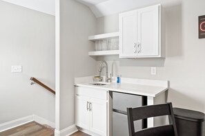 A compact kitchen with white cabinetry, a built-in dishwasher, and a small countertop. - Adam's Downtown Retreat with 2 Rooftop Patios (Clarksville)