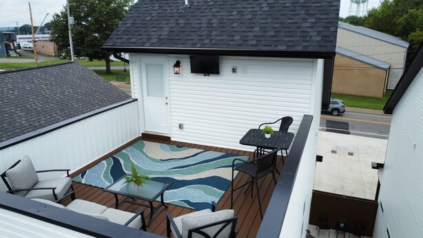 Un patio techado con una mesa y sillas, una alfombra estampada y vista a la calle.