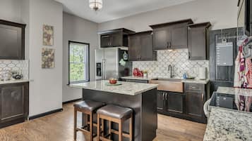 A modern kitchen with dark wood cabinets, a stainless steel refrigerator, and a granite countertop.