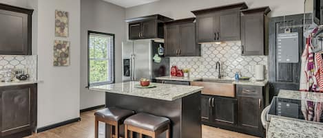 A modern kitchen with dark wood cabinets, a stainless steel refrigerator, and a granite countertop.