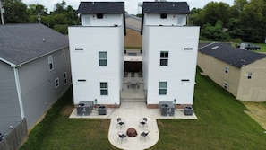 Ein zweistöckiges Gebäude mit Innenhof, Außenbereich mit Sitzgelegenheiten und einem Wasserturm im Hintergrund.