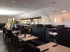 En restaurang med avskilda bås och bord, en disk med en meny och en modern inredning.