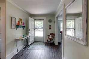 Un couloir avec une porte, une chaise, une petite table et un tapis.