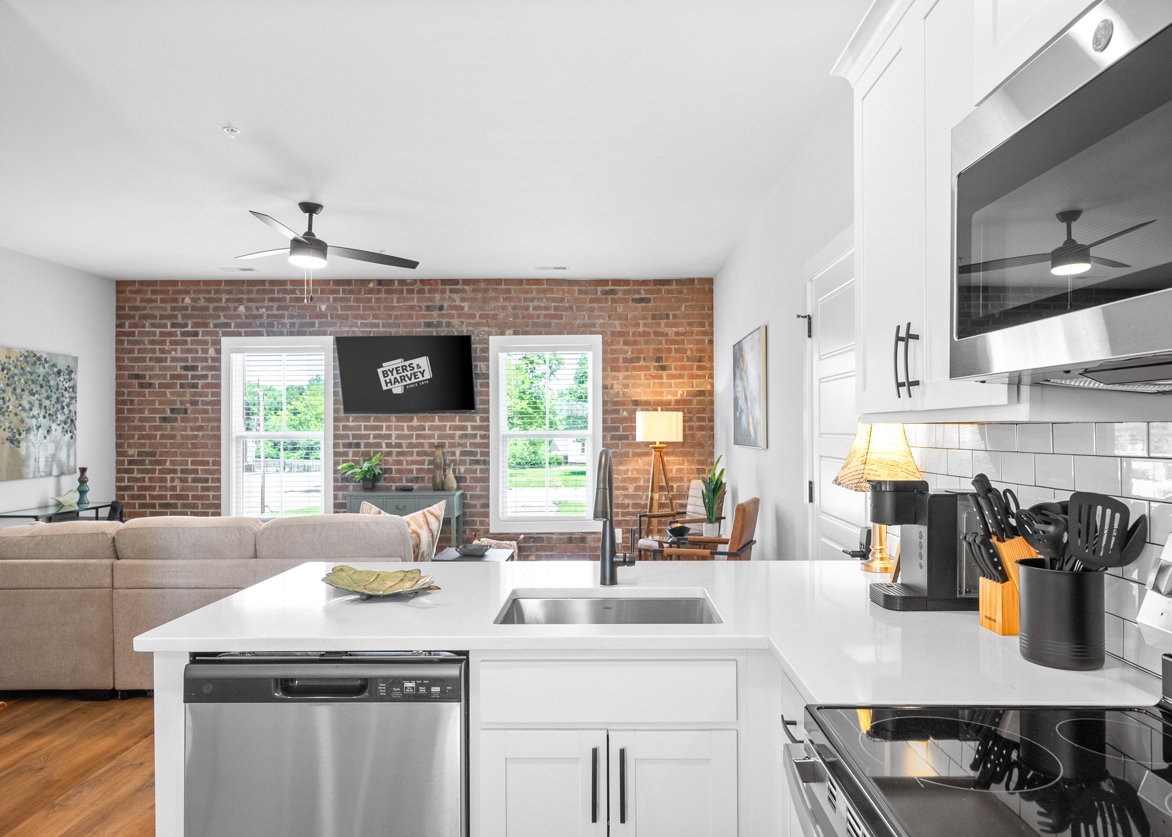 A modern kitchen with white cabinetry, a stainless steel dishwasher, and a built-in oven.