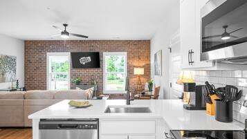A modern kitchen with white cabinetry, a stainless steel dishwasher, and a built-in oven.