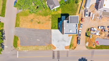 An aerial view of a residential area with a large parking lot, a swimming pool, and a building with a flat roof.
