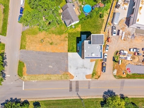 Vue aérienne d’un quartier résidentiel avec un grand parking, une piscine et un immeuble doté d’un toit plat.