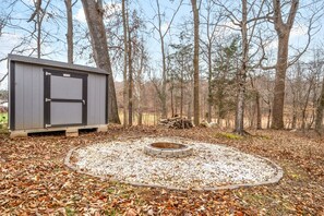 A small cabin with a stone fire pit surrounded by gravel and fallen leaves. - The Clubhouse on Colston (2296 Colston Dr) (Clarksville)