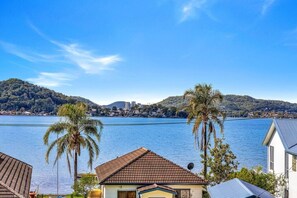 A residential area with a view of a lake and hills in the background. - Waterfront Games House | Pool & Bay Views (Koolewong)