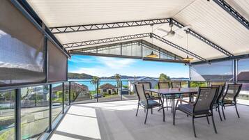A covered outdoor dining area with a view of the sea and hills.