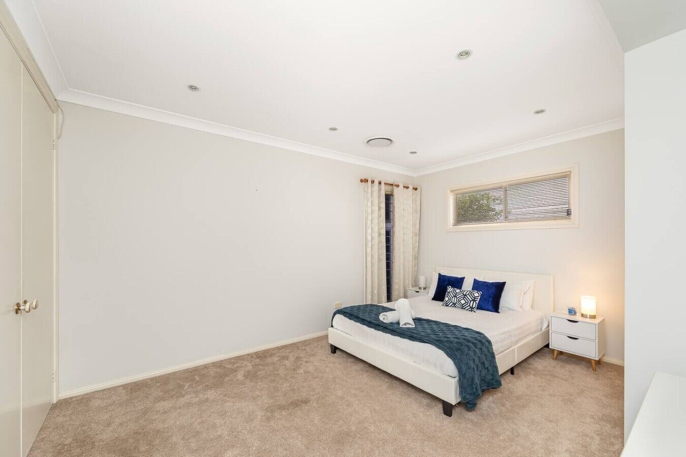 A bedroom with a bed, bedside table, and a window with curtains.