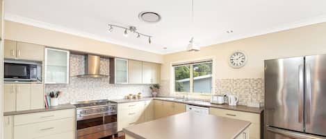 Una cocina moderna con una isla central, electrodomésticos de acero inoxidable y un amplio ventanal que ofrece luz natural.