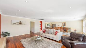 A spacious living room with a sofa, a leather armchair, and a coffee table.