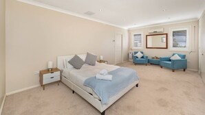 Quarto com cama, mesas de cabeceira, um sofá azul e um espelho grande.