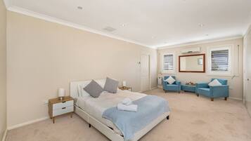 A bedroom with a bed, bedside tables, a blue sofa set, and a large mirror.