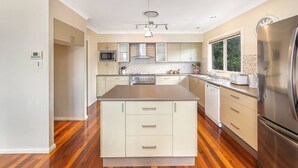 Uma cozinha moderna com uma ilha central, eletrodomésticos de aço inoxidável e uma janela que oferece luz natural.