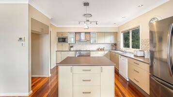 A modern kitchen with a central island, stainless steel appliances, and a window providing natural light.
