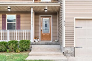 A residential house with a front porch, a welcome sign, a mailbox, and a garage door. - The Fox House (615 Fox Path) | Spacious 3-Bedroom Home in Clarksville, TN (Clarksville)