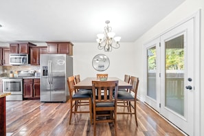 A kitchen with wooden cabinets, stainless steel appliances, a dining table with chairs, and a chandelier. - The Fox House (615 Fox Path) | Spacious 3-Bedroom Home in Clarksville, TN (Clarksville)