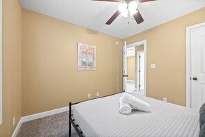 A bedroom with a bed, a ceiling fan, a door, and a wall-mounted light switch. - The Fox House (615 Fox Path) | Spacious 3-Bedroom Home in Clarksville, TN (Clarksville)