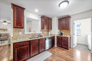 A kitchen with wooden cabinets, granite countertops, a dishwasher, and a tiled backsplash. - The Fox House (615 Fox Path) | Spacious 3-Bedroom Home in Clarksville, TN (Clarksville)