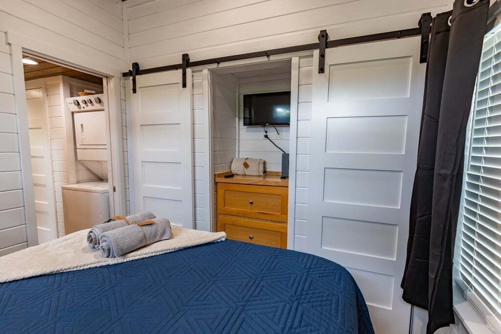Ein Schlafzimmer mit Bett, Kommode, Fernseher und einem Kleiderschrank mit Schiebetüren.