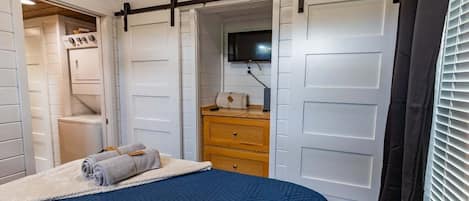 A bedroom with a bed, a dresser, a television, and a closet with sliding doors.