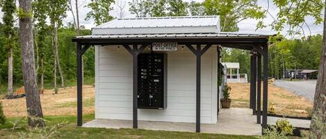 A small, single-story post office with a metal roof and a black mailbox.