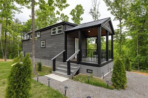 A two-story cabin with a porch, a staircase, and a small deck.