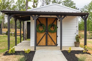 A small wooden shed with a metal roof and two wreaths on the door. - The Nesting Nook (In The Pines at KY Lake) (Dover)