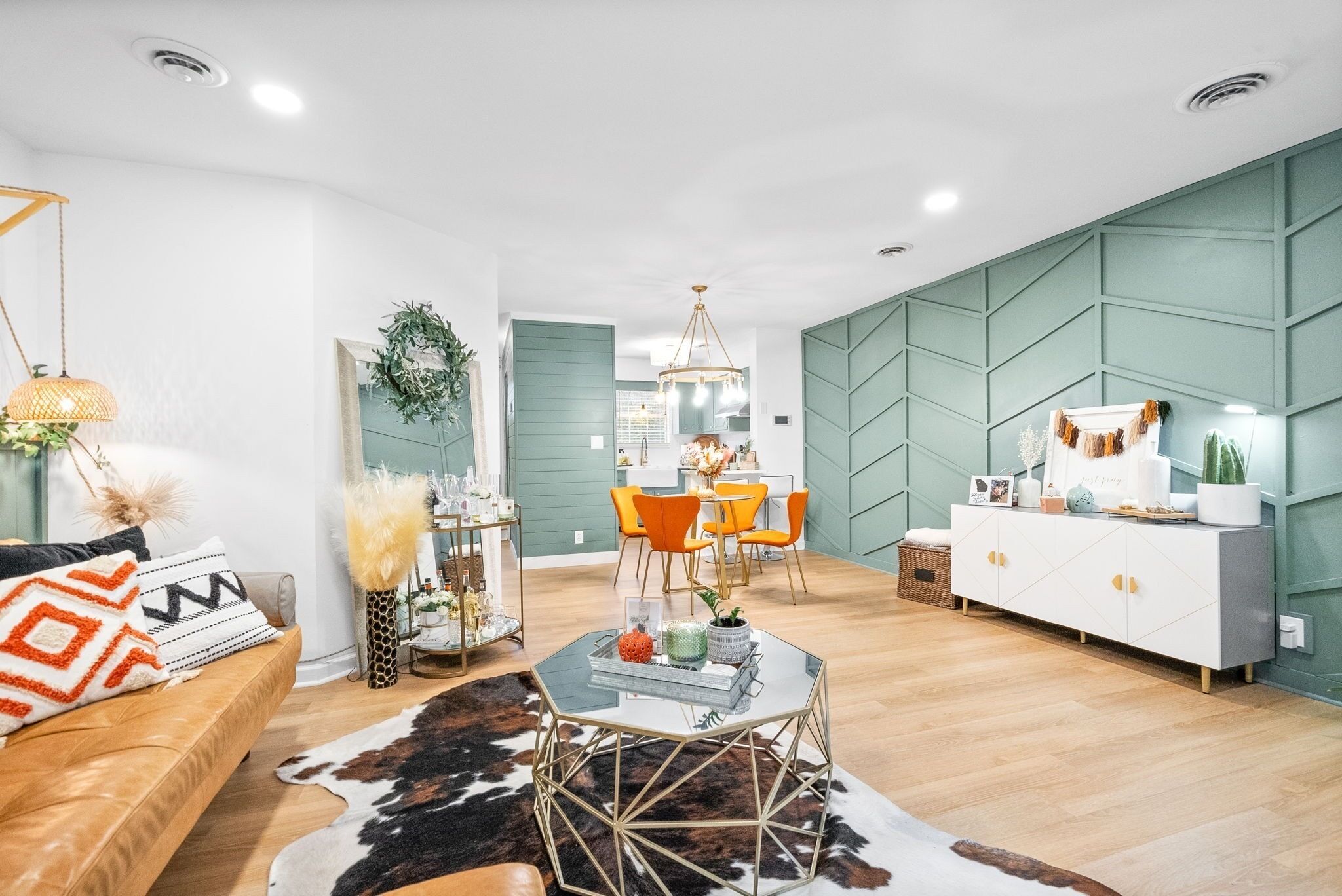 A modern living room with a sofa, coffee table, and a dining area with orange chairs.