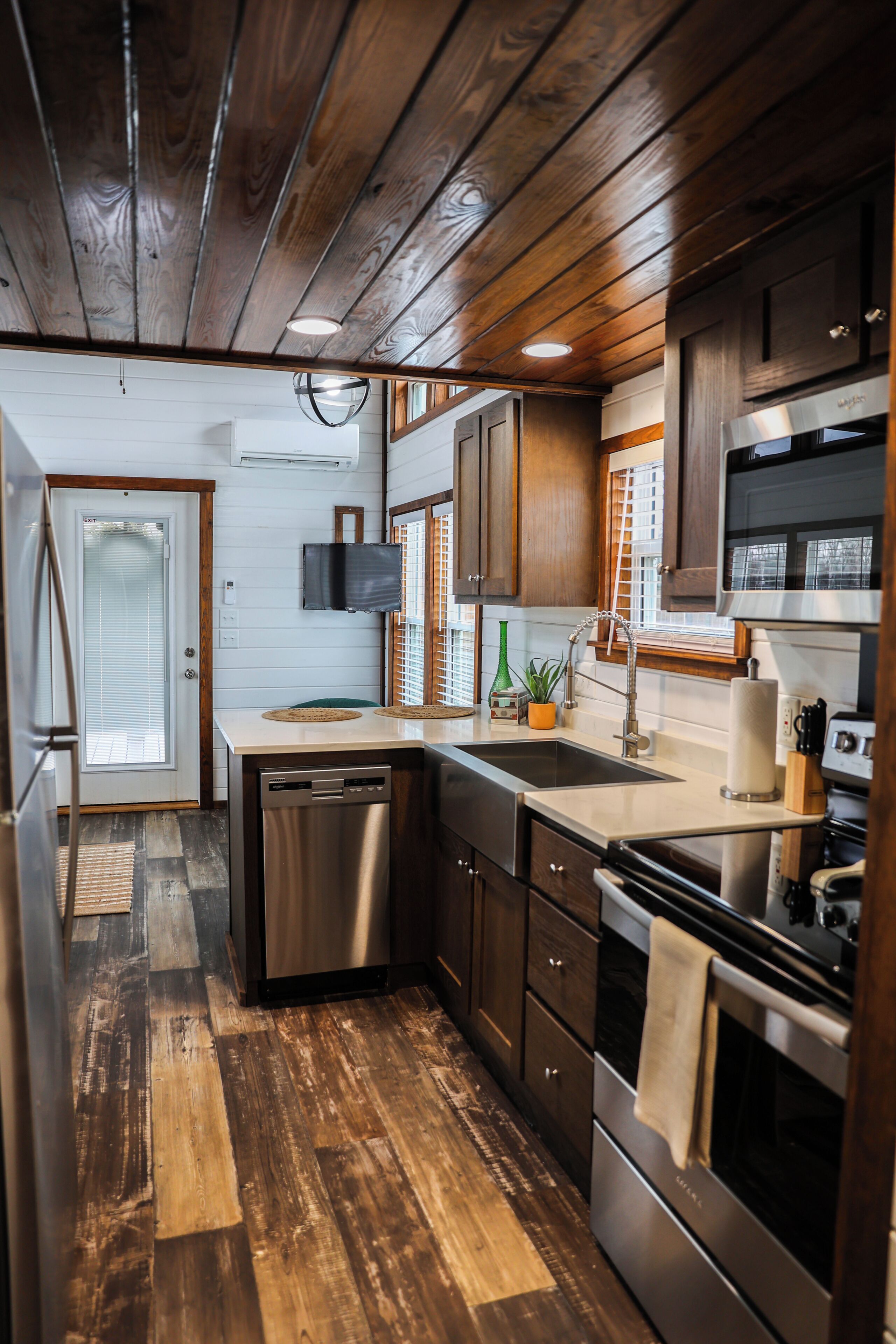 A compact kitchen with wooden flooring, stainless steel appliances, and a built-in oven.