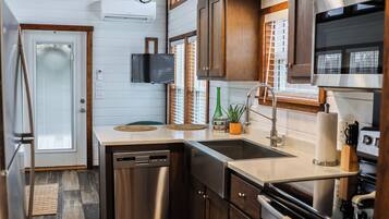 A compact kitchen with wooden flooring, stainless steel appliances, and a built-in oven.