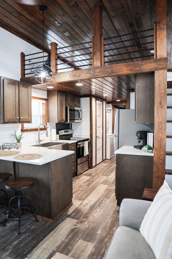 Una cocina moderna con vigas de madera, electrodomésticos de acero inoxidable y una isla central.