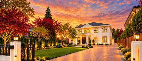 A large, two-story house with a driveway leading to the entrance, surrounded by trees and well-maintained landscaping.