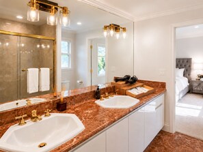 A modern bathroom with a double sink, gold fixtures, and a large mirror. - Breezery Retreat (Richmond)