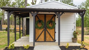 A small wooden shed with a metal roof and two wreaths on the door.