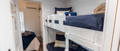 A bunk bed room with white walls and wooden flooring.