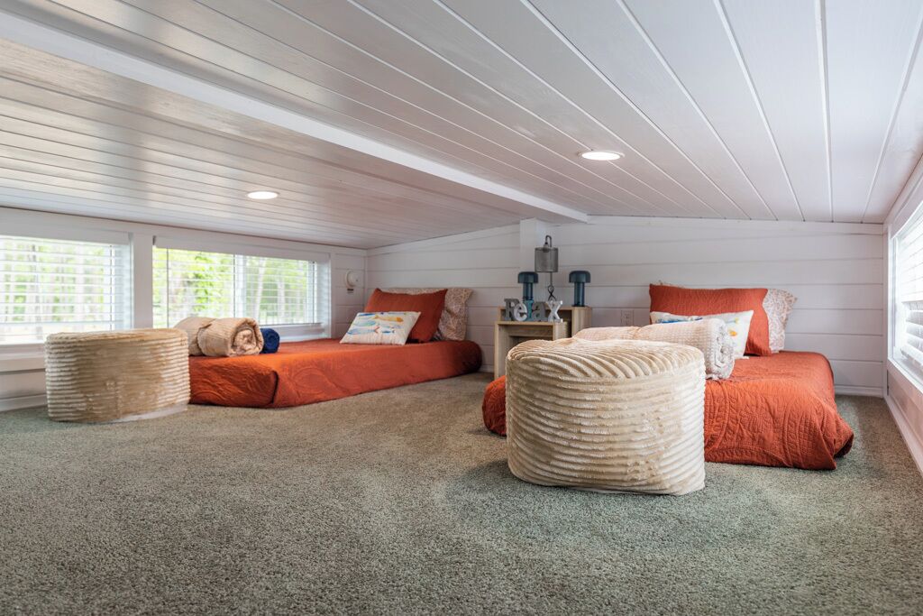 A bedroom with two beds, a nightstand, and a window with blinds.