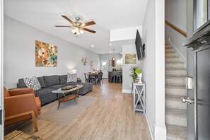 A modern living room with a gray sofa, coffee table, and a ceiling fan.