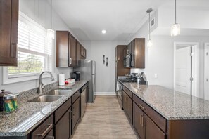 Eine moderne Küche mit Granit Arbeitsplatten, Edelstahlgeräten und Holzschränken.