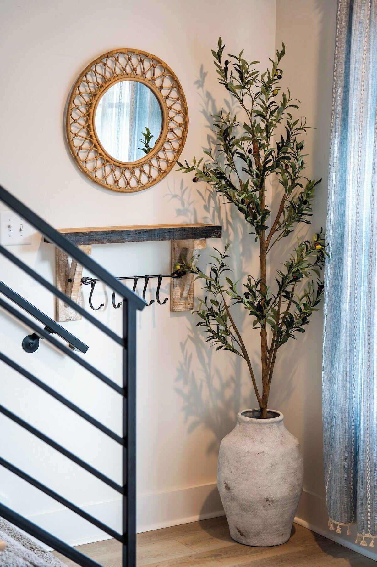 A staircase with a handrail, a wall-mounted mirror, a potted plant, and a decorative wall piece.