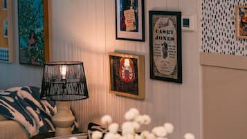 Una stanza accogliente con un tavolo rotondo, un vaso con fiori bianchi, una lampada a sospensione e quadri appesi alle pareti.
