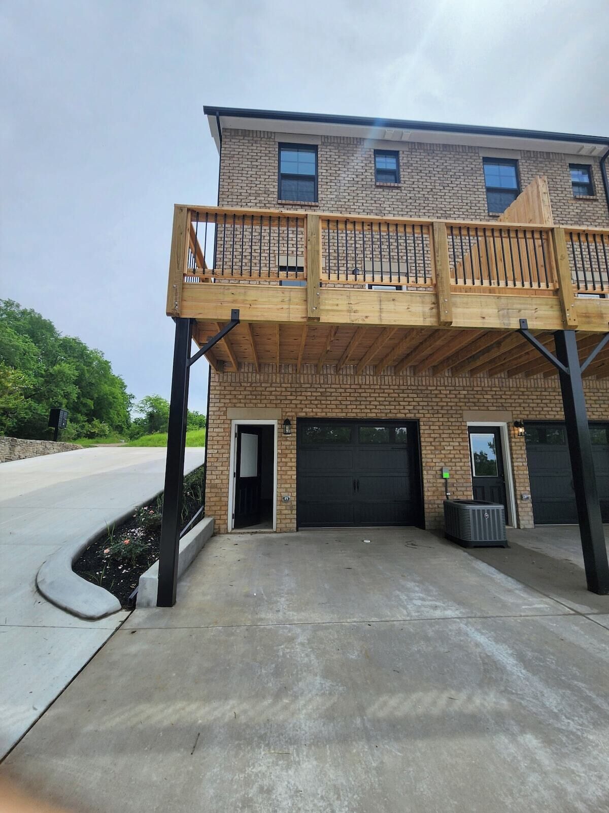 A two-story building with a wooden balcony, brick facade, and two garages.