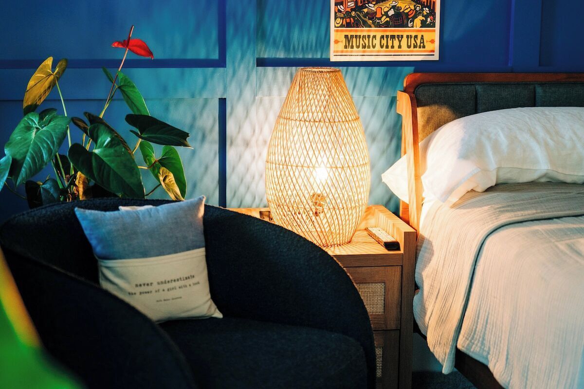 Une chambre à coucher avec un lit, une table de chevet, une lampe et une affiche accrochée au mur.