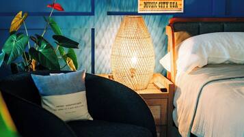 Une chambre à coucher avec un lit, une table de chevet, une lampe et une affiche accrochée au mur.