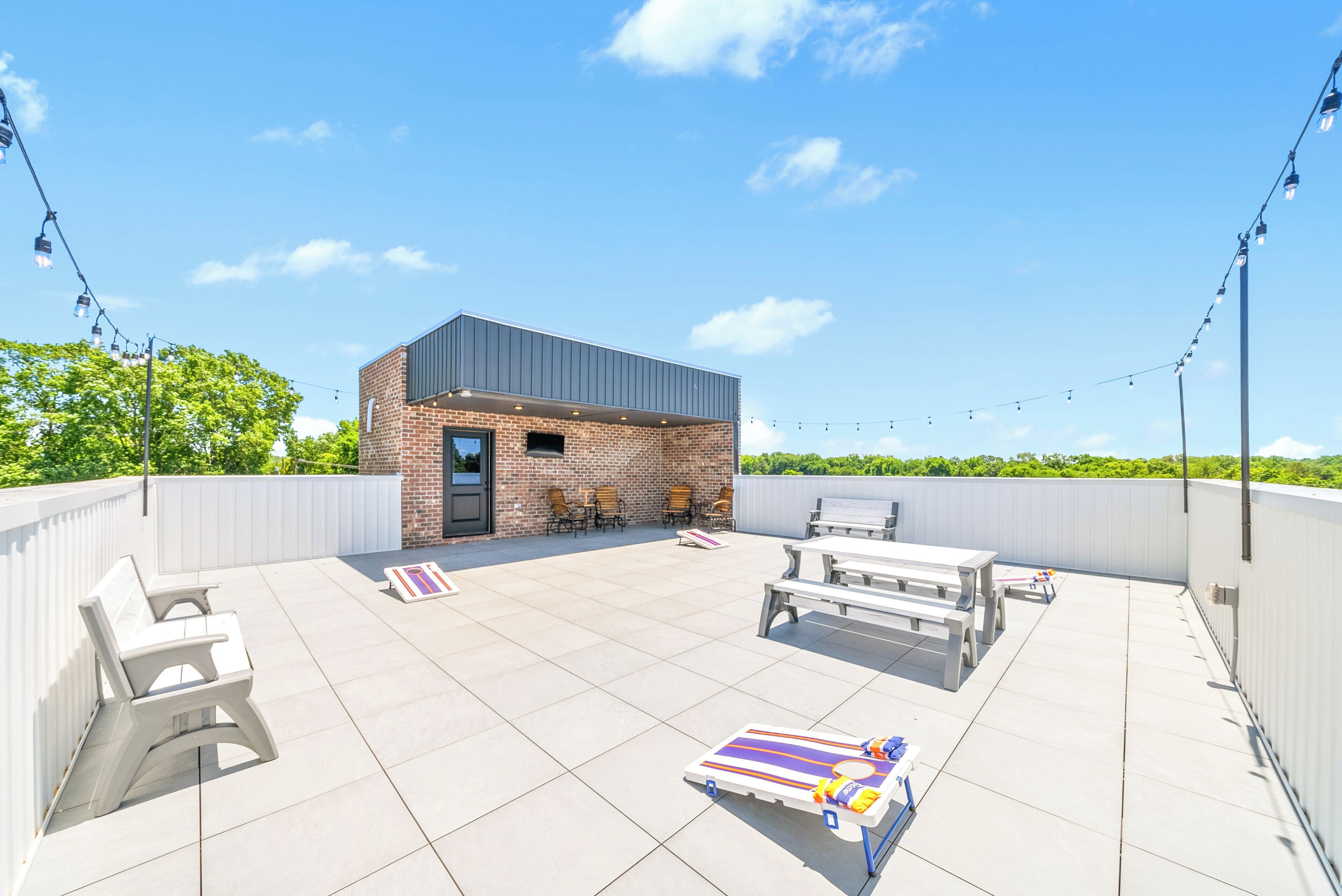 A rooftop patio with a small brick building, outdoor seating, and string lights.