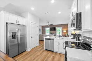 Une cuisine moderne dotée d’appareils électroménagers en acier inoxydable, de meubles blancs et d’un plancher en bois.